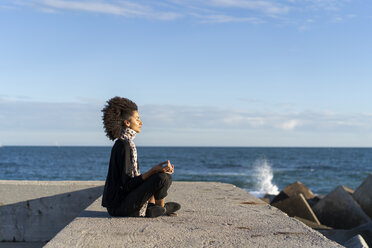 Frau sitzt an der Wand vor dem Meer und meditiert - AFVF02106