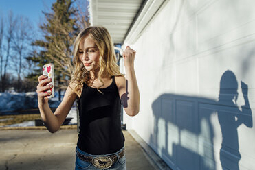 Mädchen nimmt Selfie beim Stehen durch Haus - CAVF59687