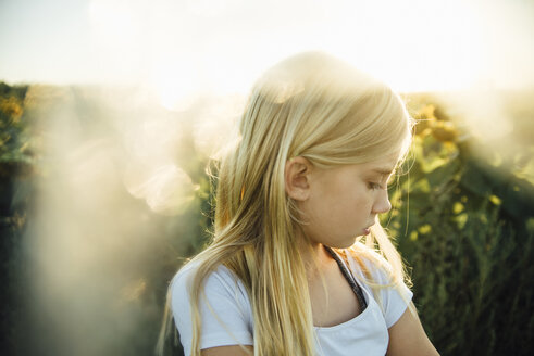 Nahaufnahme eines Mädchens auf einem Sonnenblumenfeld - CAVF59693