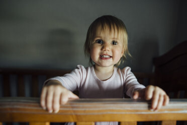 Portrait of smiling girl in crib at home - CAVF59706