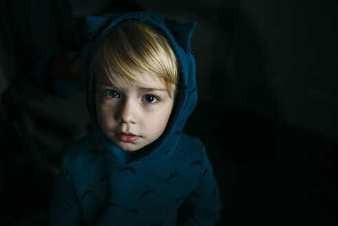 Hochformatiges Porträt eines süßen Jungen mit Kapuzenhemd in der Dunkelkammer - CAVF59726