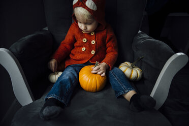 Cute boy playing with pumpkins at home during Halloween - CAVF59730