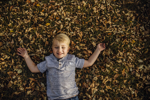 Hohe Winkel Ansicht der fröhlichen Jungen auf gefallenen Herbstblätter im Park liegen - CAVF59738