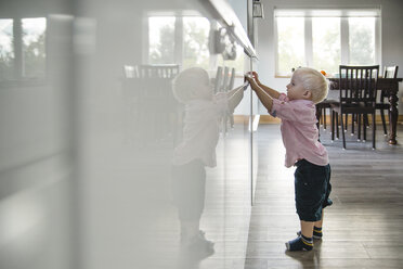 Seitenansicht eines süßen Jungen, der zu Hause mit der Spülmaschine spielt - CAVF59751