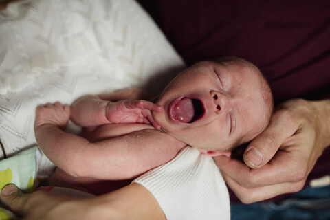 Nahaufnahme einer Mutter, die ihre gähnende Tochter zu Hause trägt, lizenzfreies Stockfoto