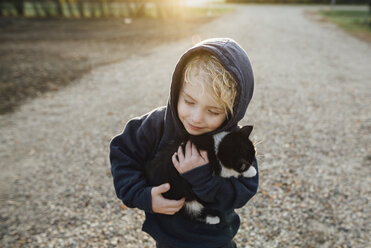 Hohe Winkel Ansicht der niedlichen Jungen umarmt Katze im Park - CAVF59766