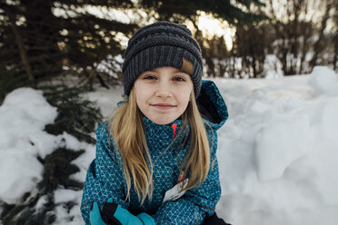Portrait of girl sitting on snow field - CAVF59787