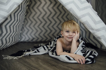 Porträt eines Jungen mit Hand am Kinn, der zu Hause im Zelt liegt - CAVF59792