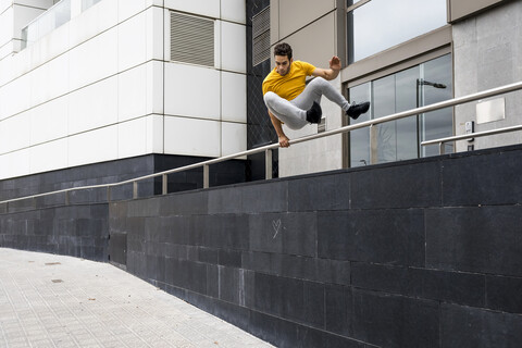 Junger Mann springt über Geländer, lizenzfreies Stockfoto