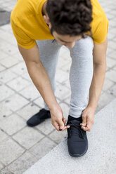 Junger Mann beim Trainieren, Schuhe binden - MAUF01873