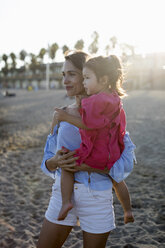 Mutter und Tochter stehen bei Sonnenuntergang am Strand - MAUF01900