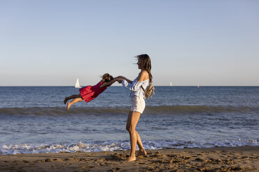 Mutter und Tochter haben Spaß am Strand und tun so, als würden sie fliegen - MAUF01906