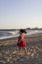 Cute little girl standing on the beach, looking at the sea - MAUF01913