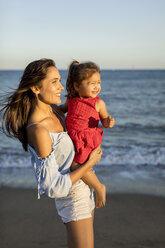 Mother and daughter standing on the beach at sunset - MAUF01928