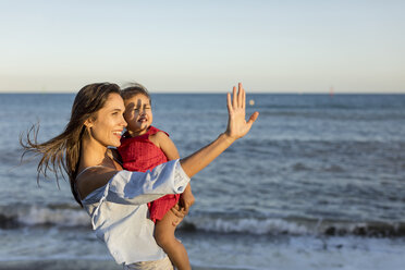 Mother and daughter standing on the beach at sunset - MAUF01929