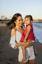 Mother and daughter standing on the beach at sunset - MAUF01930