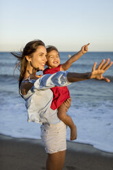 Mother and daughter standing on the beach at sunset - MAUF01931