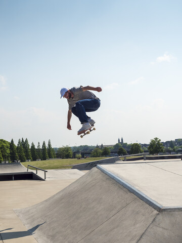 Junger Mann beim Schlittschuhlaufen im Skatepark, lizenzfreies Stockfoto