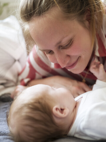 Lächelnde Mutter, die ihre kleine Tochter streichelt, lizenzfreies Stockfoto