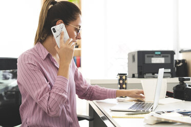 Designer, der im Büro arbeitet, einen Laptop benutzt und telefoniert - ERRF00343