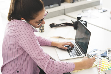 Designer, der im Büro arbeitet, einen Laptop benutzt und telefoniert - ERRF00345