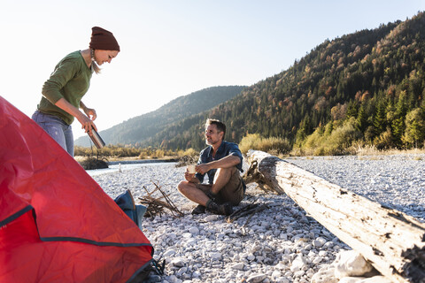 Älteres Paar beim Zelten am Flussufer im Abendlicht, lizenzfreies Stockfoto