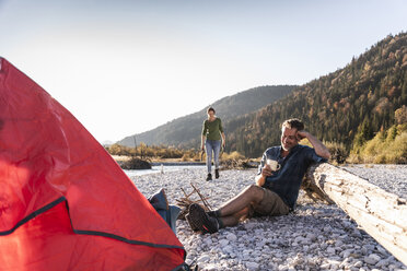 Mature couple camping at riverside in the evening light - UUF16275