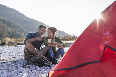 Mature couple camping at riverside in the evening light - UUF16276