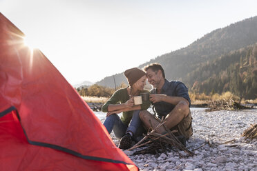 Mature couple camping at riverside in the evening light - UUF16278