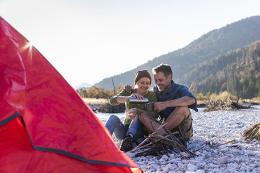 Mature couple camping at riverside in the evening light - UUF16280