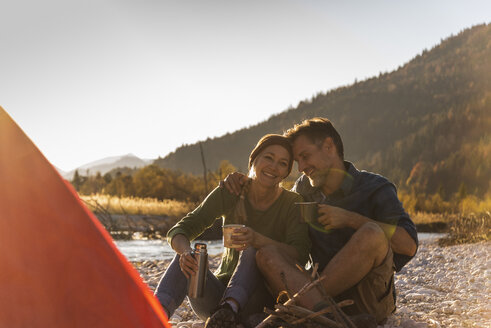 Mature couple camping at riverside in the evening light - UUF16281