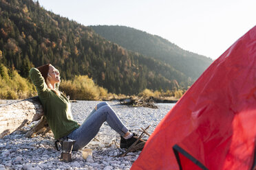 Mature woman camping at riverside in the evening light - UUF16299