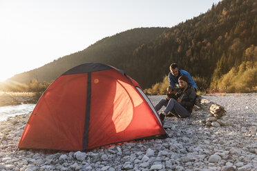 Mature couple camping at riverside in the evening light - UUF16311