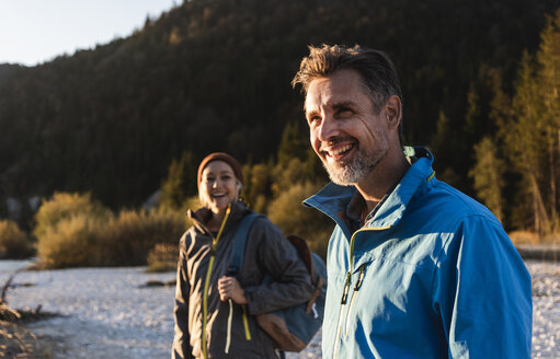 Älteres Paar beim Wandern am Flussufer im Abendlicht - UUF16319