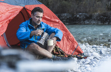 Älterer Mann beim Zelten am Flussufer, Espressomaschine und Tasse - UUF16325