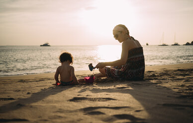 Thailand, Koh Lanta, Mutter spielt mit kleiner Tochter am Strand bei Sonnenuntergang - GEMF02653