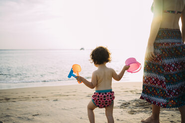 Thailand, Koh Lanta, back view of baby girl with toys on the beach by sunset - GEMF02654