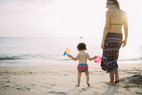 Thailand, Koh Lanta, Rückenansicht eines kleinen Mädchens und seiner Mutter am Strand bei Sonnenuntergang - GEMF02655