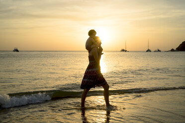 Thailand, Koh Lanta, Silhouette einer Mutter mit einem kleinen Mädchen auf den Schultern am Meeresufer bei Sonnenuntergang - GEMF02657