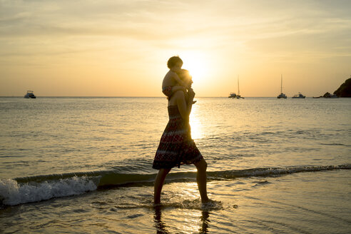 Thailand, Koh Lanta, silhouette of mother with baby girl on her shoulders at seashore during sunset - GEMF02657