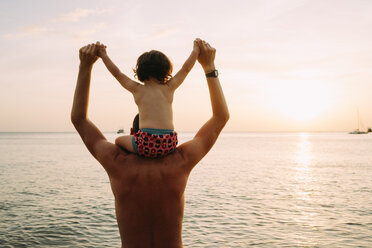 Thailand, Koh Lanta, Rückenansicht eines Vaters mit einem kleinen Mädchen auf seinen Schultern, das den Sonnenuntergang am Strand beobachtet - GEMF02659
