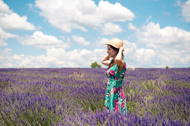 France, Provence, Valensole plateau, woman with straw hat standing in lavender field in summer - GEMF02660