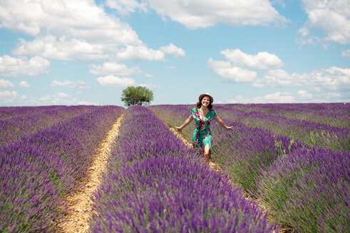 Frankreich, Provence, Hochebene von Valensole, glückliche Frau beim Spaziergang zwischen Lavendelfeldern im Sommer - GEMF02662