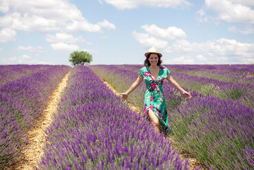 Frankreich, Provence, Hochebene von Valensole, lächelnde Frau, die im Sommer zwischen Lavendelfeldern spazieren geht - GEMF02663