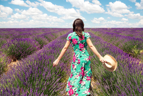 Frankreich, Provence, Hochebene von Valensole, Rückenansicht einer Frau im Sommerkleid in einem Lavendelfeld - GEMF02664