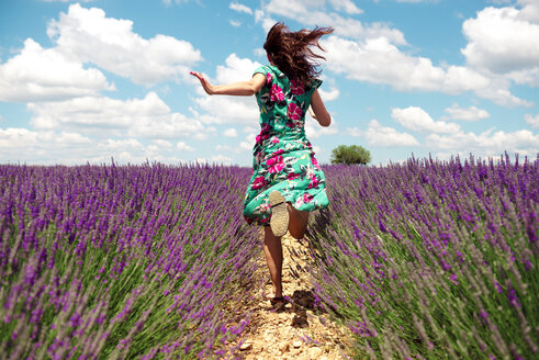 France, Provence, Valensole plateau, back view of woman running among lavender fields in summer - GEMF02667