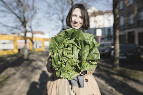 Lächelnde Frau zeigt einen Salatkopf, Nahaufnahme, lizenzfreies Stockfoto