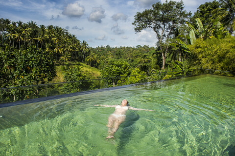 Indonesien, Bali, Ubud, Kamandalu Ubud Resort, Frau genießt den herrlich überlaufenden Pool, lizenzfreies Stockfoto