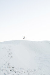 Distant view of woman jumping at White Sands National Monument against clear sky - CAVF59842