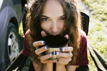 Close-up portrait of woman having drink at campsite - CAVF59865